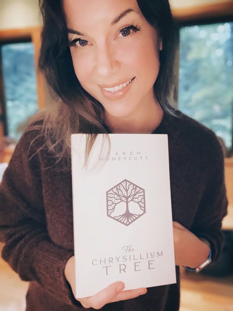 Laken Honeycutt holding a printed copy of her novel The Chrysillium Tree