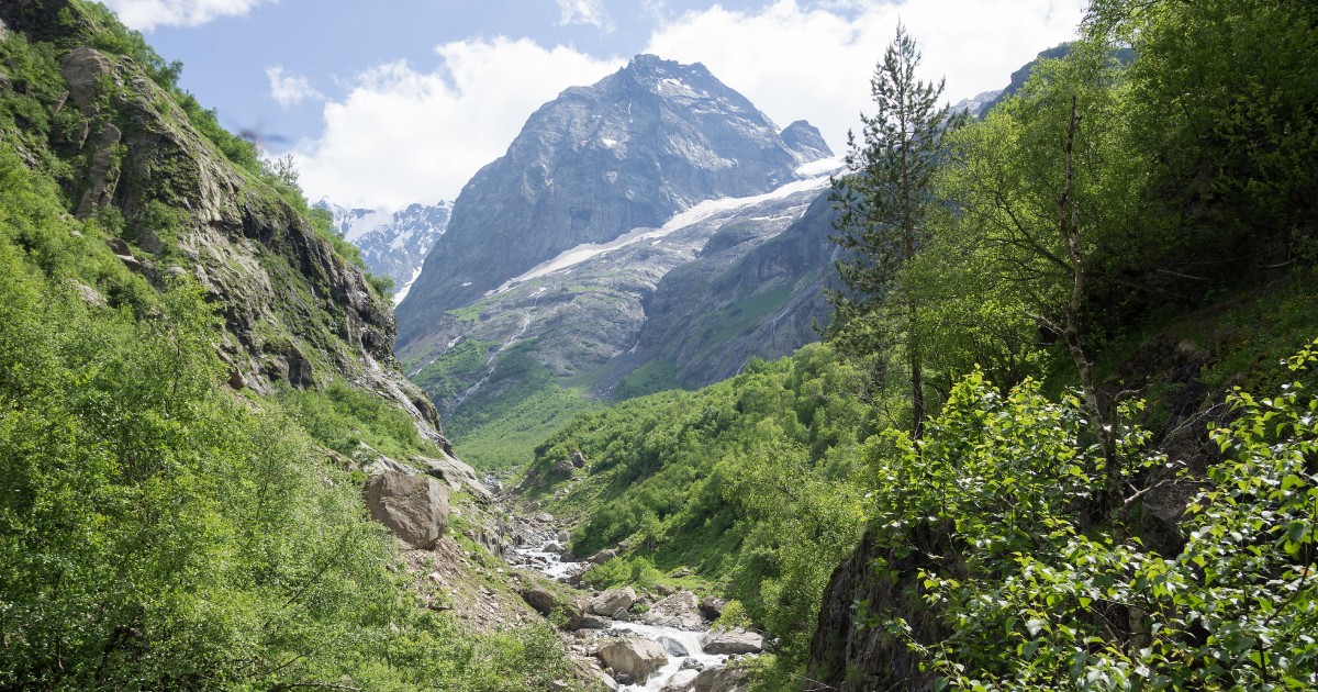 A valley with steep green sides and a high mountain in the background